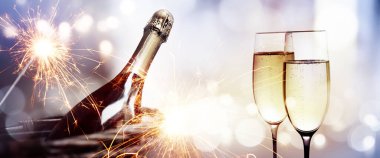 Cheers with a bottle of champagne for a new year on sparkeling background and bright bokeh clipart