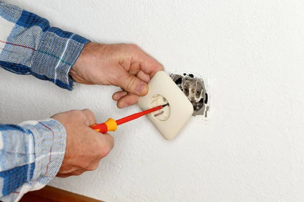 worker is mounting an electrical socket into a wall