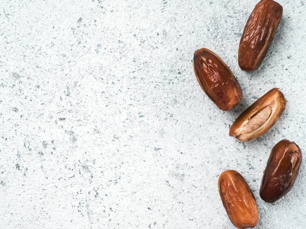 Sweet raw dates on gray cement background. Whole dates and half with bone date on grey concrete surface. Sugar free alternatives concept with space for text. Top view or flat-lay.