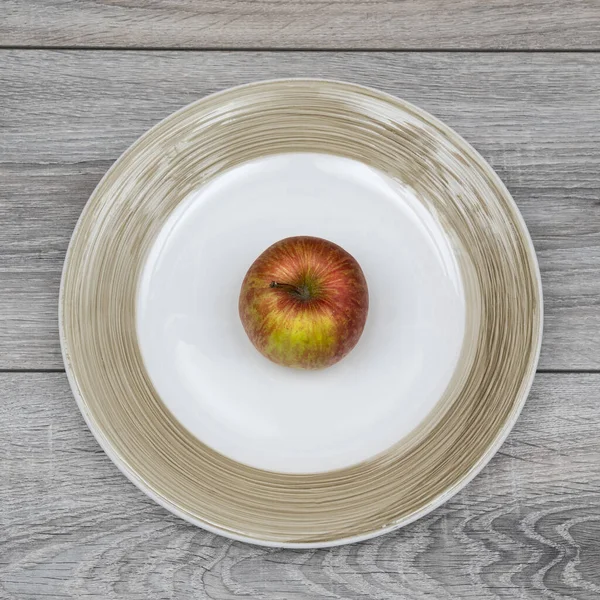 Ένα Κόκκινο Μήλο Στο Πιάτο Ένα Ξύλινο Τραπέζι — Φωτογραφία Αρχείου
