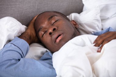Portrait Of A Young African Man Sleeping On Bed clipart