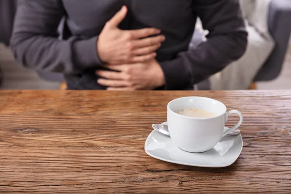 Mann Leidet Unter Bauchschmerzen Mit Tasse Kaffee Auf Holztisch — Stockfoto