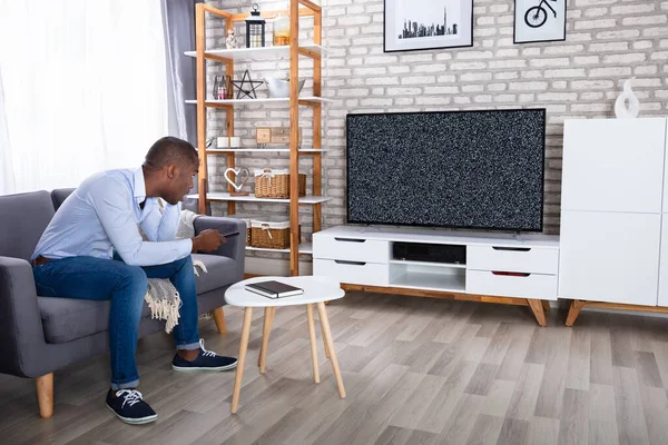African Man Siedzi Łóżku Patrząc Telewizję Bez Sygnału — Zdjęcie stockowe