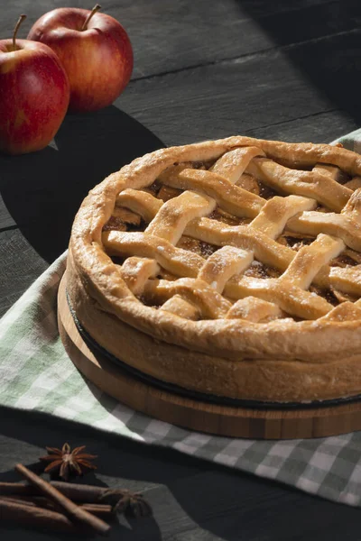 一个美味的自制苹果派 有晶格外壳 在切菜板和厨房毛巾上 在乡村的桌子上 在自然光下的垂直图像 — 图库照片