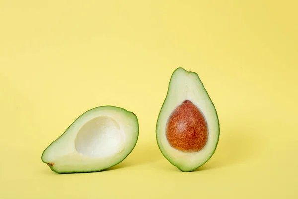Two slices of avocado isolated on  yellow background with shadows . One slice with core. Design element for product label.