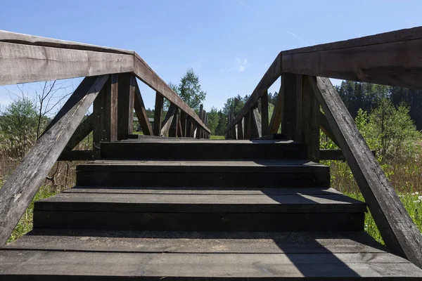小さな川の向こうにある険しい木の橋への階段で入口を始めます — ストック写真