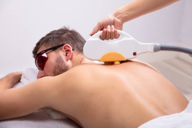 Close-up Of Man Receiving Laser Epilation Treatment By Beautician In Spa clipart