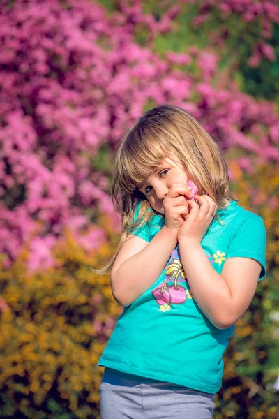 春の花が色鮮やかなピンクと黄色開花前でポーズ少女 — ストック写真