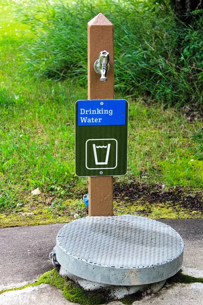 Ein Trinkwasserschild Neben Einer Brunnenabdeckung — Stockfoto