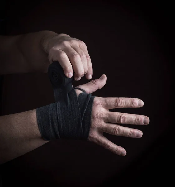 男人把双手包在黑色的纺织品绷带里 用于运动 黑色的背景 — 图库照片