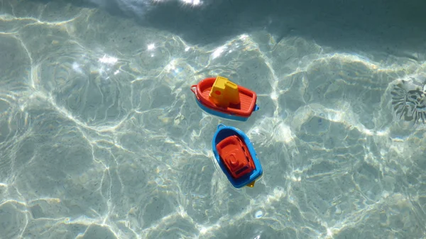 透明水に浮かぶ明るい色の子供のビーチおもちゃのボート — ストック写真