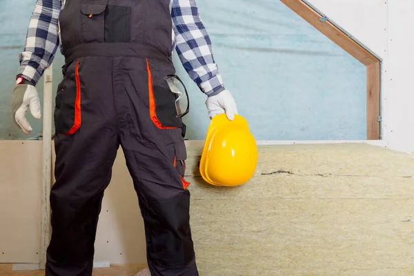 Man installing thermal roof insulation layer - using mineral wool panels. Attic renovation and insulation concept