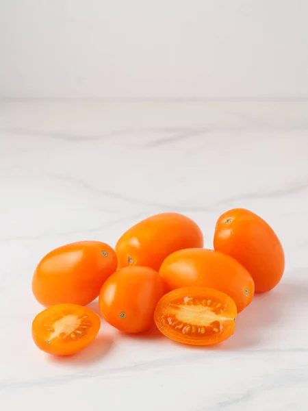 白い大理石のテーブルの上にオレンジトマト 黄色またはオレンジのトマトのヒープは 2つの半分スライストマトと テキストのコピースペース — ストック写真