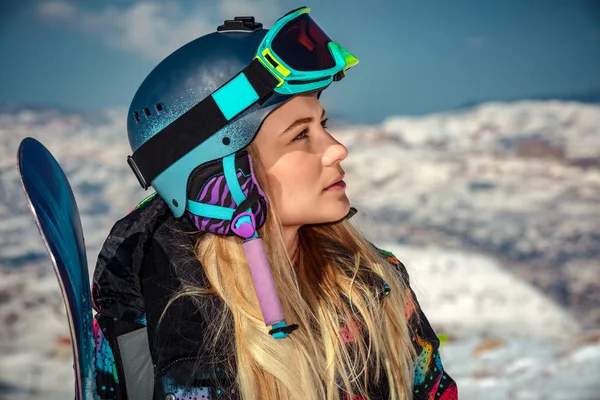 一个戴着头盔和面罩的女运动员的画像 手里拿着雪板 望着旁边 享受着阳光灿烂的霜冻天气 是登上雪板的完美日子 — 图库照片