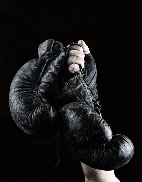 Поднял Руку Человека Держит Пару Старых Черных Кожаных Боксерских Перчаток — стоковое фото