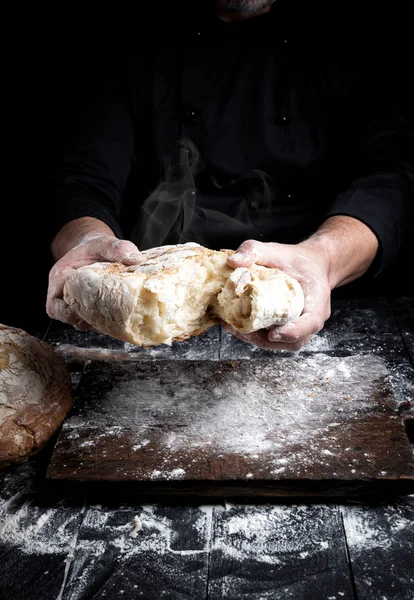 Mężczyzna Ręce Łamiąc Otwarty Pieczony Chleb Pół Nad Czarnym Drewnianym — Zdjęcie stockowe