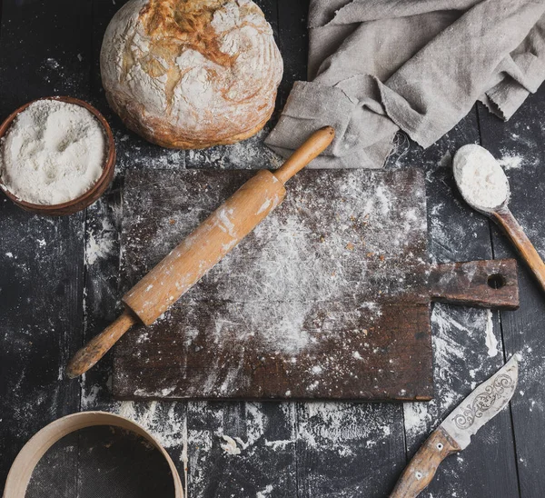 焼きたてのパン 白い小麦粉 木製麺棒と黒いテーブル トップ ビューで古いまな板 — ストック写真