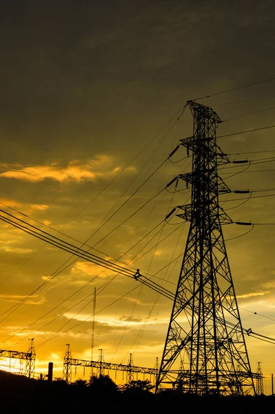 高電圧を高電圧投稿タワー シルエットの高電圧の夕焼けオレンジ黄色背景大国に投稿 — ストック写真