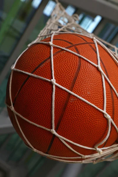 关闭一个篮球挂在网袋里 低角度侧视 — 图库照片