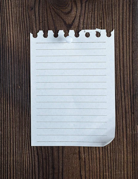 茶色の木製の表面ボタンに添付された空のメモ帳紙 — ストック写真