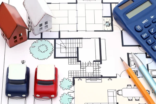 Miniature model of house, car and blueprints, construction plan