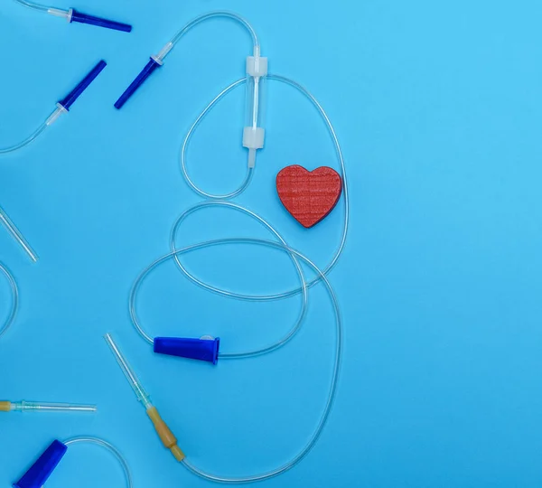 Пустая Пластиковая Капельница Иглами Красным Сердцем Синем Фоне Медицинское Устройство — стоковое фото