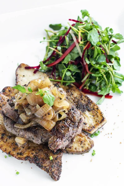 牛肉牛排与烤蘑菇和焦糖洋葱在白色盘子上的美餐 — 图库照片