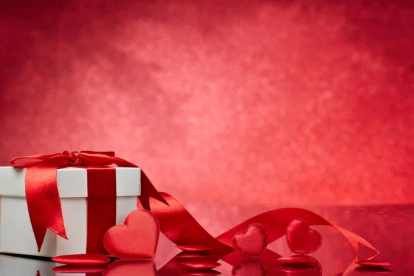 赤い背景にギフトボックスと赤いサテンの心 コピースペースのバレンタインデーカード ロマンチックなグリーティングカード 結婚式の招待状 女性の日のポストカードのためのデザイン要素 — ストック写真