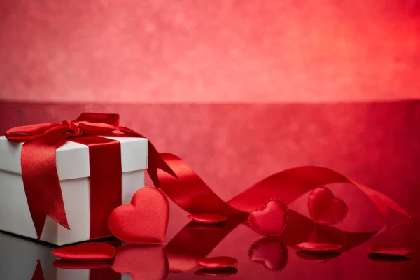 赤い背景にギフトボックスと赤いサテンの心 コピースペースのバレンタインデーカード ロマンチックなグリーティングカード 結婚式の招待状 女性の日のポストカードのためのデザイン要素 — ストック写真