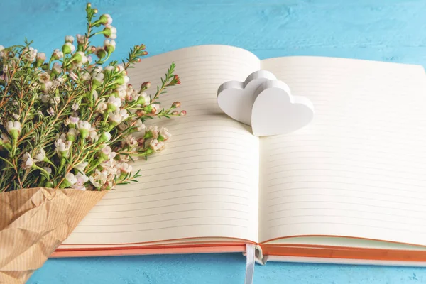 Kleine Witte Bloemen Boeket Een Leeg Notitieblok Twee Houten Harten — Stockfoto