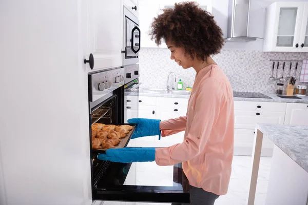 Happy Young Woman Wearing Blue Mitt Removing Baked Croissants Tray — Stock Photo, Image