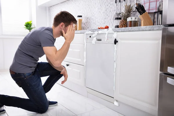 Homem Perturbado Sentado Frente Máquina Lavar Louça Danificada Com Espuma — Fotografia de Stock