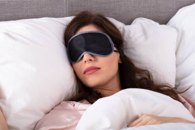 Close-up Of Beautiful Young Woman Sleeping On Bed With Eye Mask clipart