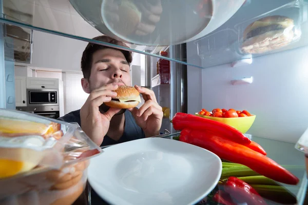 Közeli Kép Egy Éhes Fiatal Ember Eszik Hamburgert Közelében Hűtőszekrény — Stock Fotó