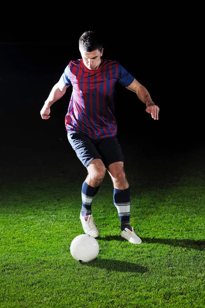 サッカー選手は夜に黒の背景に隔離されたサッカー競技場でボールでキックをする — ストック写真