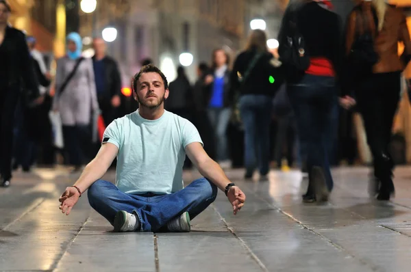年轻人在晚上在街头的莲花位置冥想瑜伽 — 图库照片