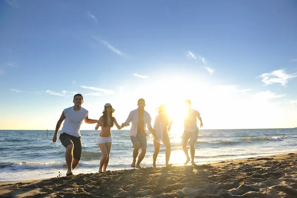 幸せな若い友人グループは楽しい時間を過ごし 夕日のビーチでジャンプして走りながらお祝いします — ストック写真