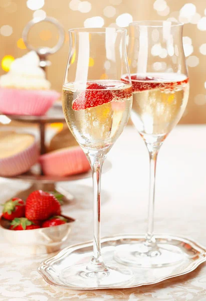Romantic champagne and strawberries served on a silver tray in elegant flutes with festive party lights