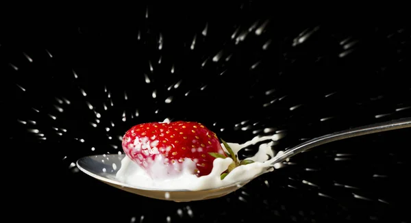 stock image red,ripe strawberry falling in spoon with fresh milk - isolated on paint background