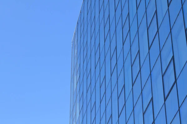 Nowoczesna Przeszklona Fasada Biurowej Wieży Przed Błękitnym Niebem — Zdjęcie stockowe