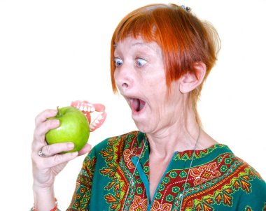 Woman losing her false teeth by biting into an apple clipart