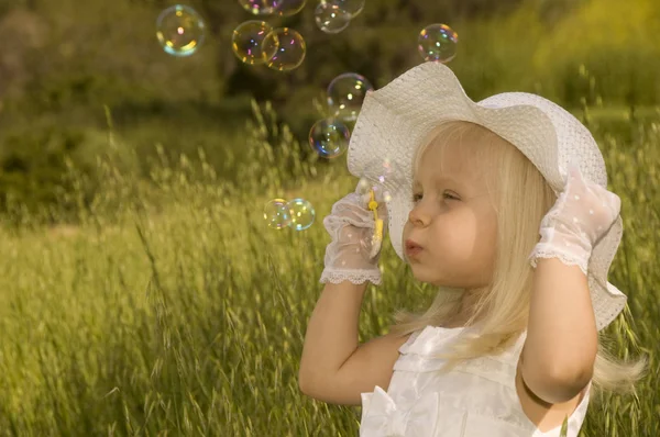 Κοριτσάκι Λευκό Φόρεμα Και Καπέλο Φυσάει Σαπουνόφουσκες Χωράφι — Φωτογραφία Αρχείου