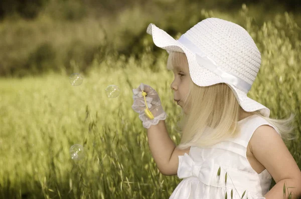 Little Girl White Dress Hat Blowing Soap Bubbles Field — Stock Photo, Image