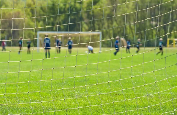 足球运动员通过球门网看球 关注球门网的前景 — 图库照片