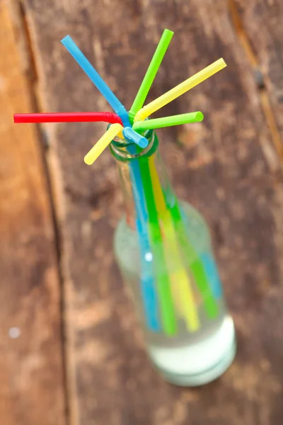 果実酒を含むガラス瓶の首から放射されるカラフルな飲料ストローの配置浅いDof — ストック写真