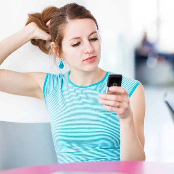 Pretty young woman using her mobile phone/speaking on the phone in a public area (shallow DOF