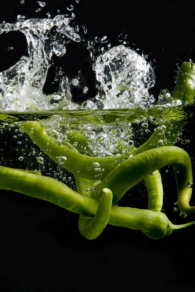 Zielona Papryka Wrzucane Wody Czarnym Tle — Zdjęcie stockowe