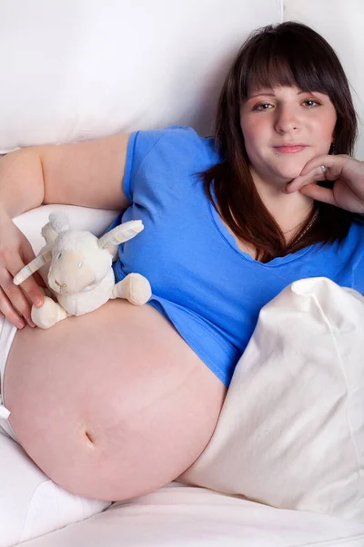 怀孕的年轻女子 肚子上有柔软的玩具 — 图库照片