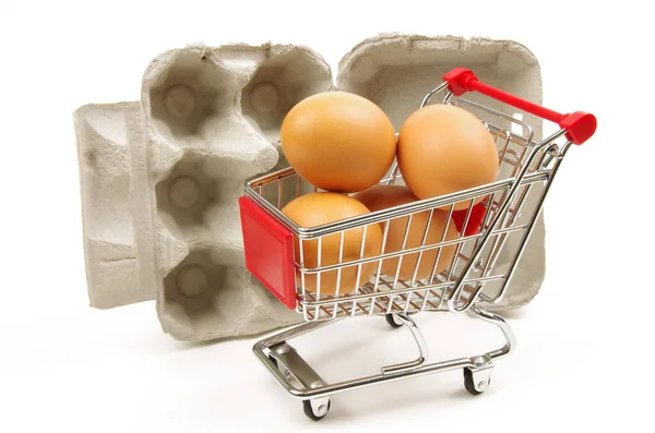 白い背景に茶色の卵と空の卵の箱を持つ赤いショッピングトロリー — ストック写真