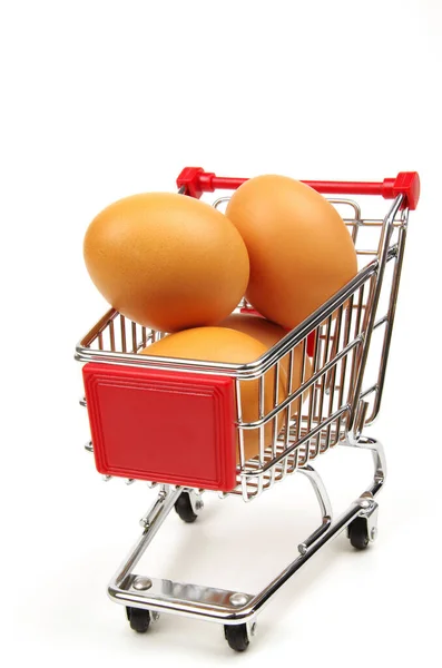 白い背景に赤いスーパーマーケットのトロリーと新鮮な茶色の卵 — ストック写真